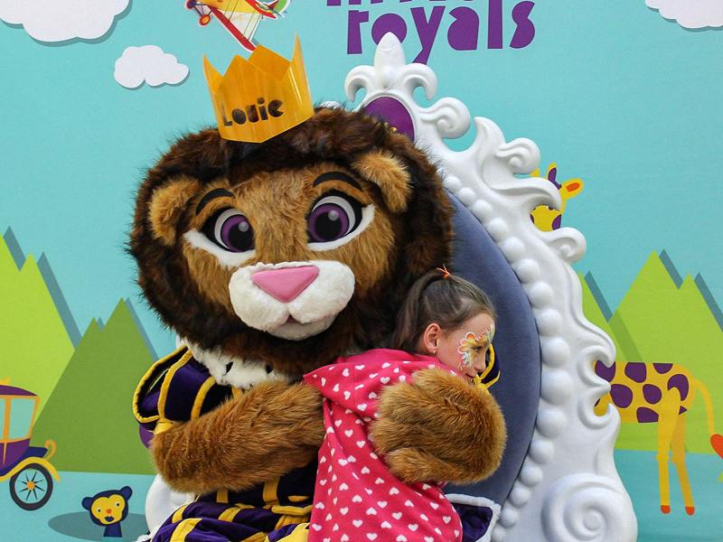 Louie hugging a young girl at a Little Royals kids club event